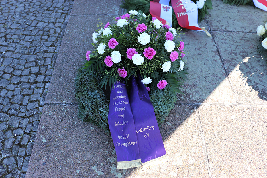 Kranz mit violetten und weißen Blüten und violetter Schleife. (Foto: Gedenkstätte Ravensbrück)